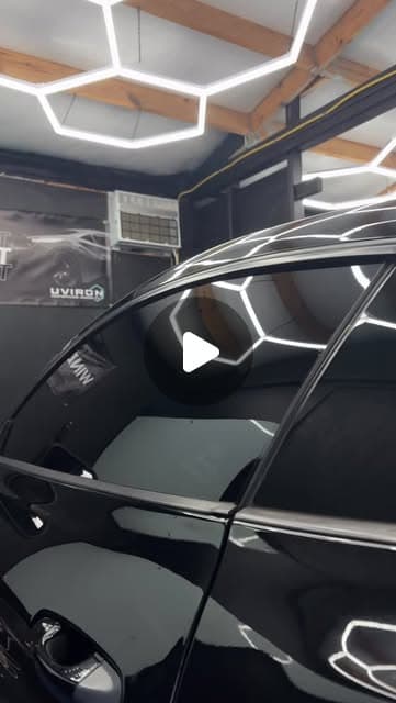 Black car with freshly installed window tint under studio lighting